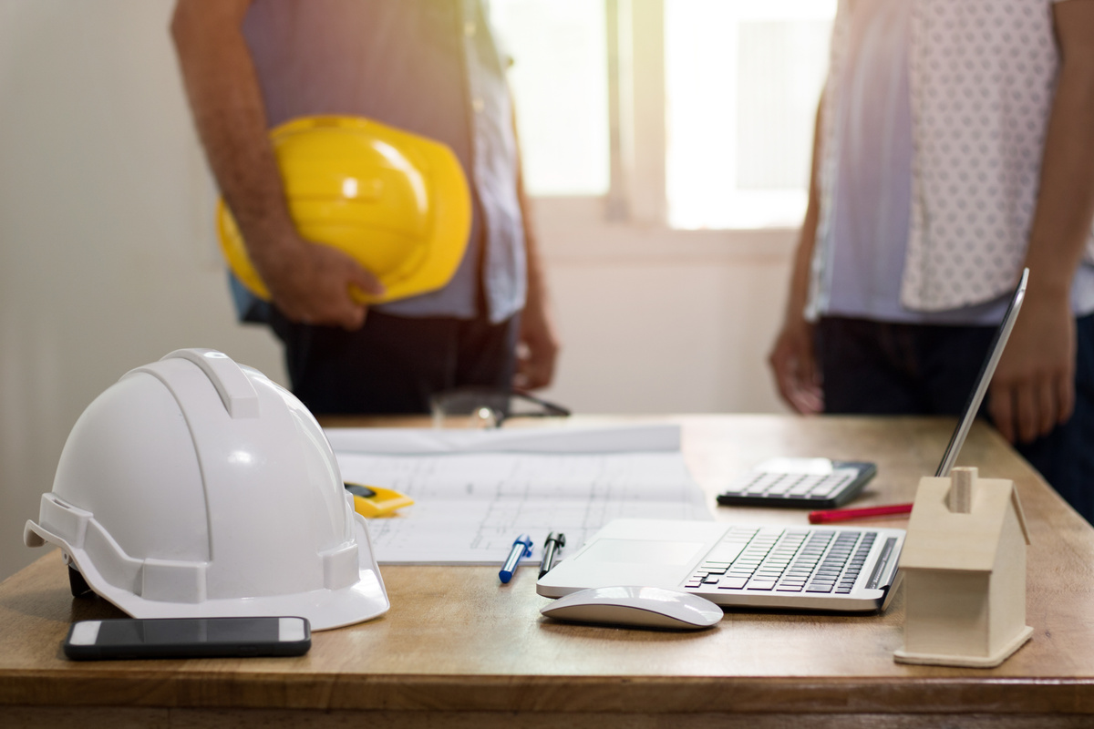 Focus at Safty Helmet on Working Desk and Two Engineer Standing